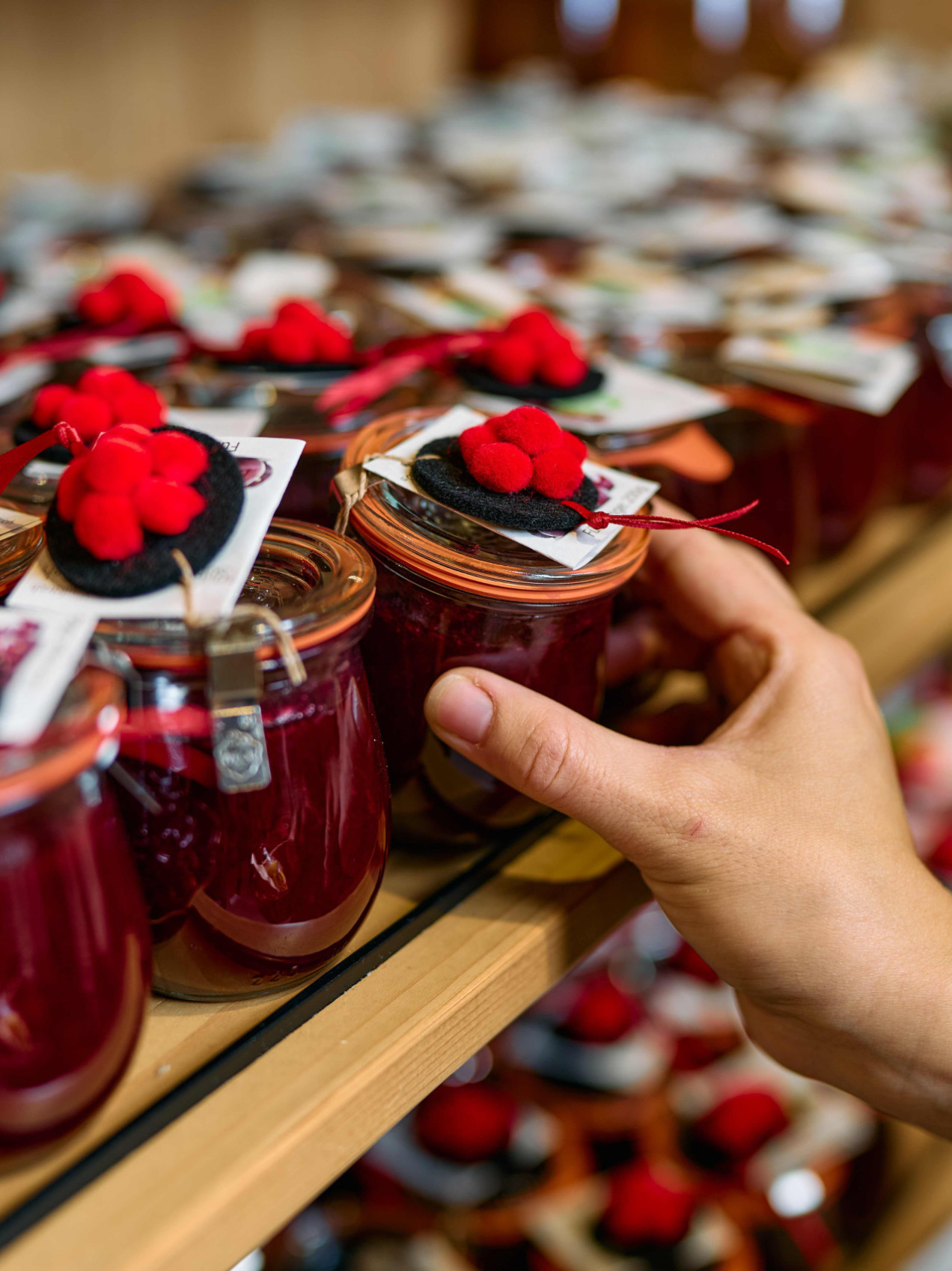 handgemachte schwarzwälder Kirschmarmelade wird aus dem Regal der Markt-Scheune gegriffen von einer Hand.