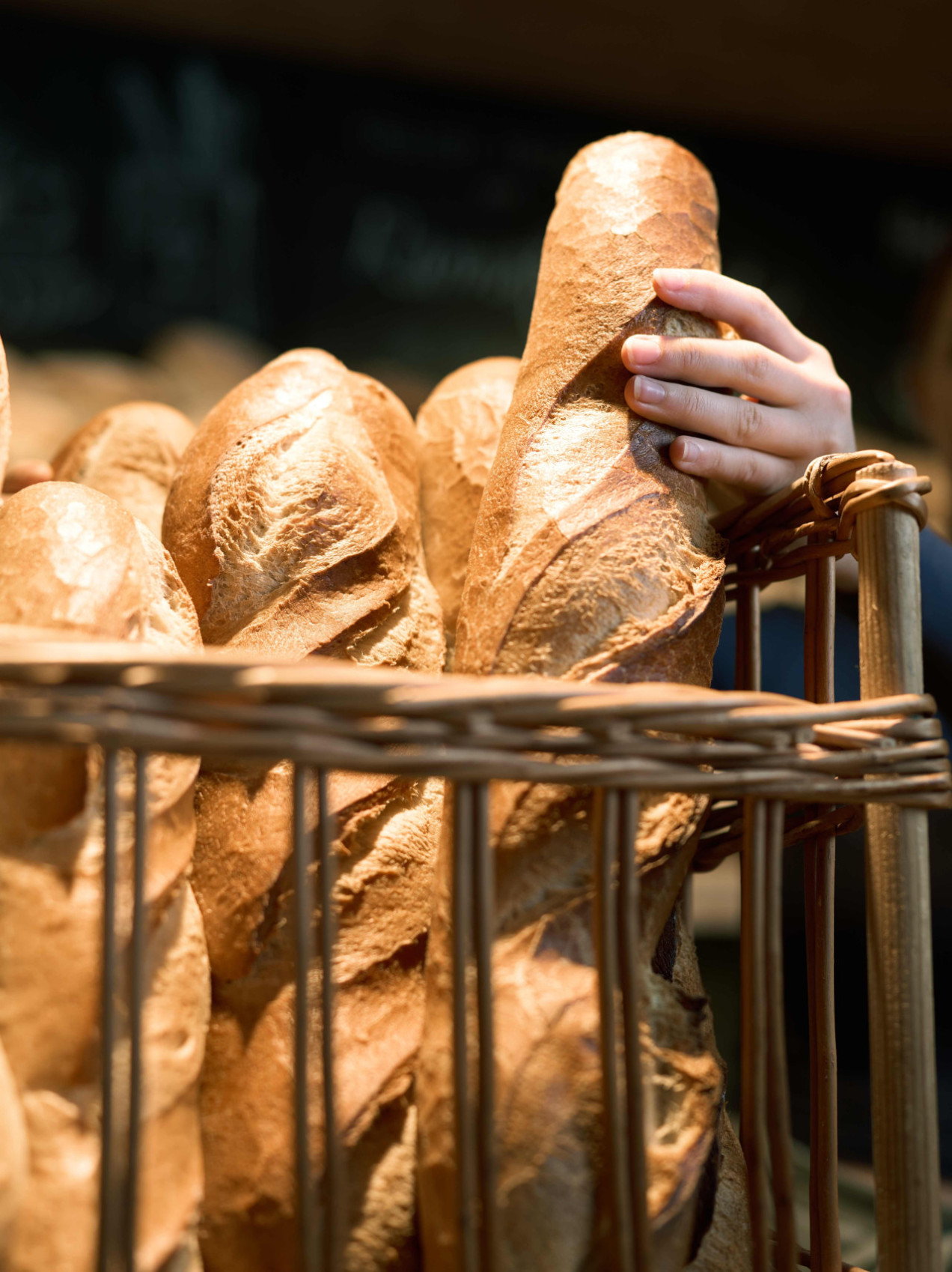 Frisches Baguette vom Ramsteinerhof in Fischerbach steht im Baguette Korb und wird von einer Mitarbeiterin gerade entnommen.