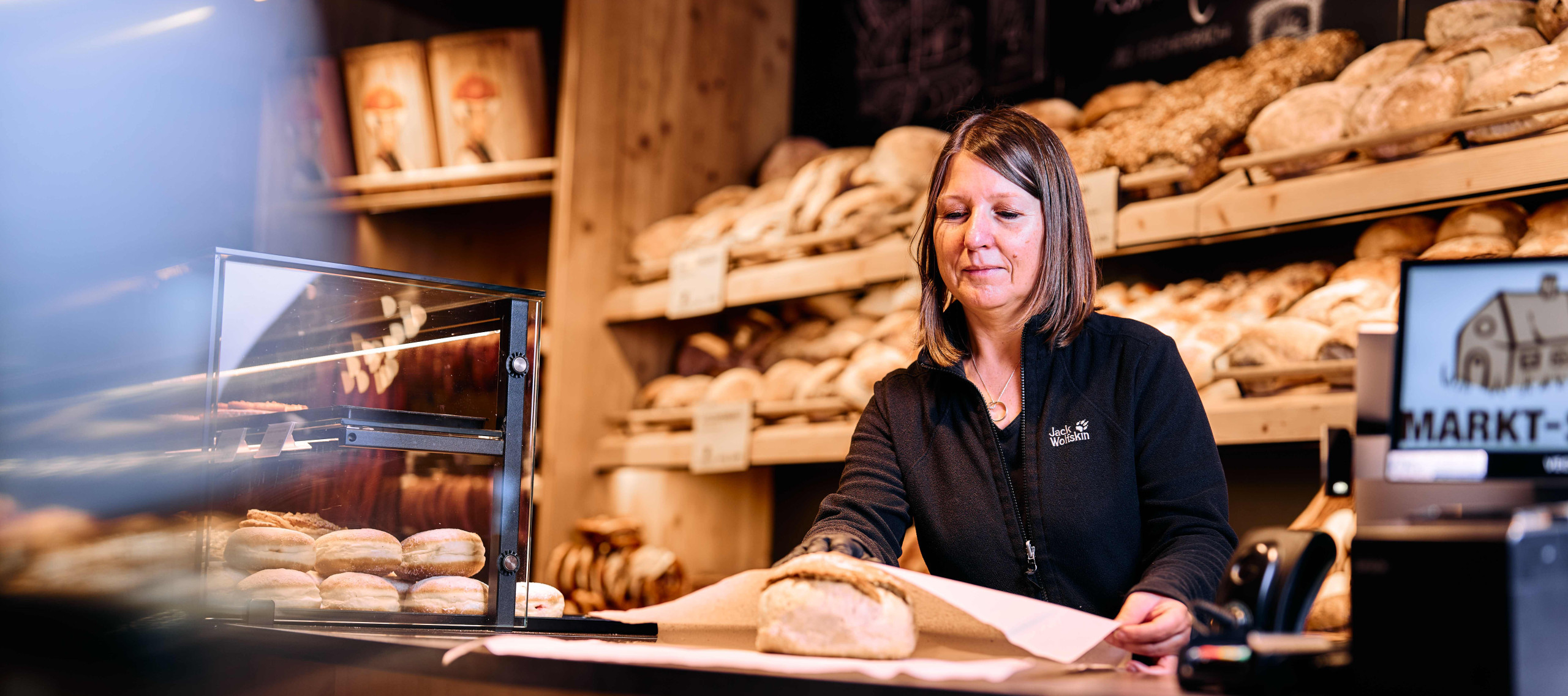 Von einer Mitarbeiterin der Markt-Scheune wird frisches, knuspriges Holzofenbrot eingepackt.